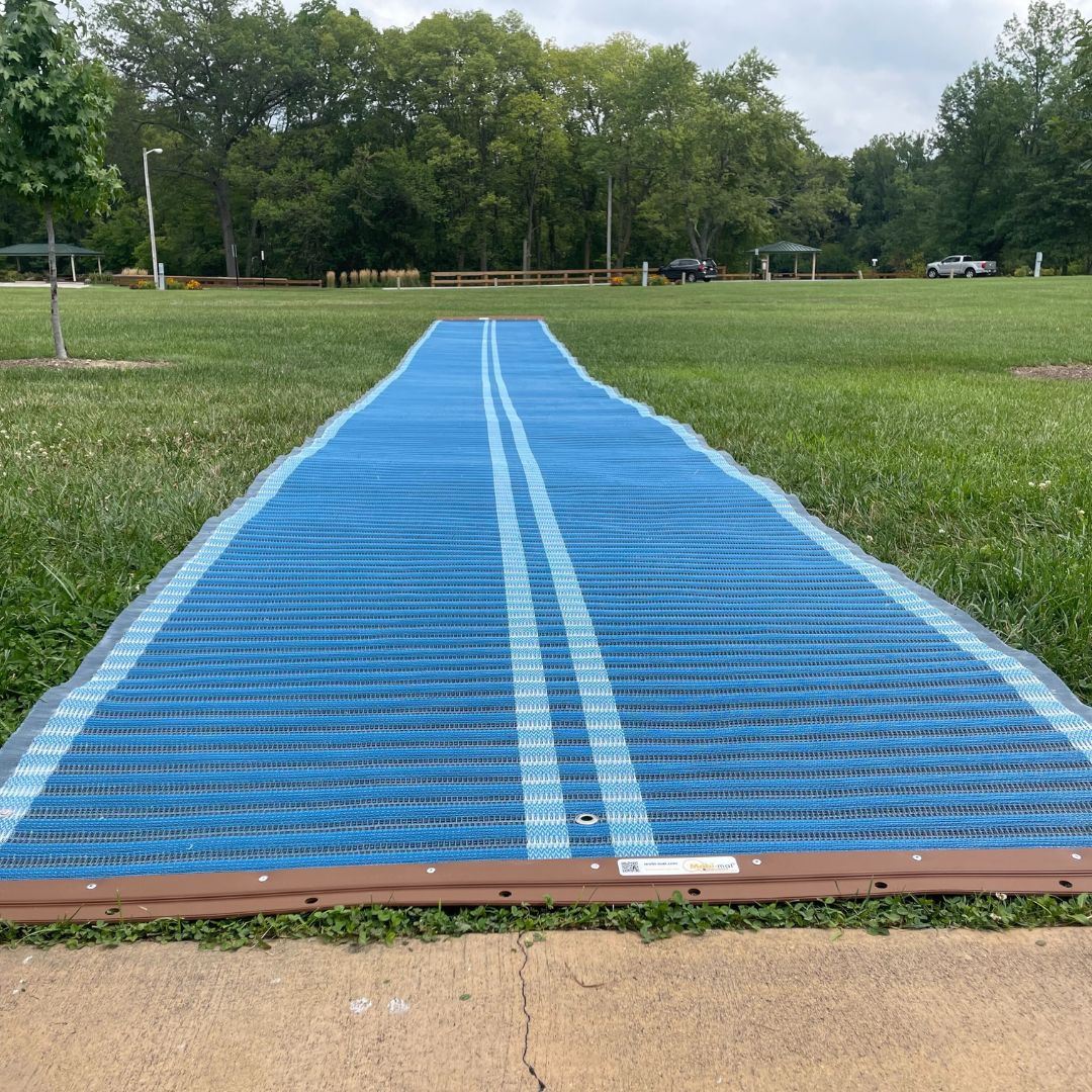 A roll-out mat that provides a firm surface for wheelchair and walker access into grassy areas
